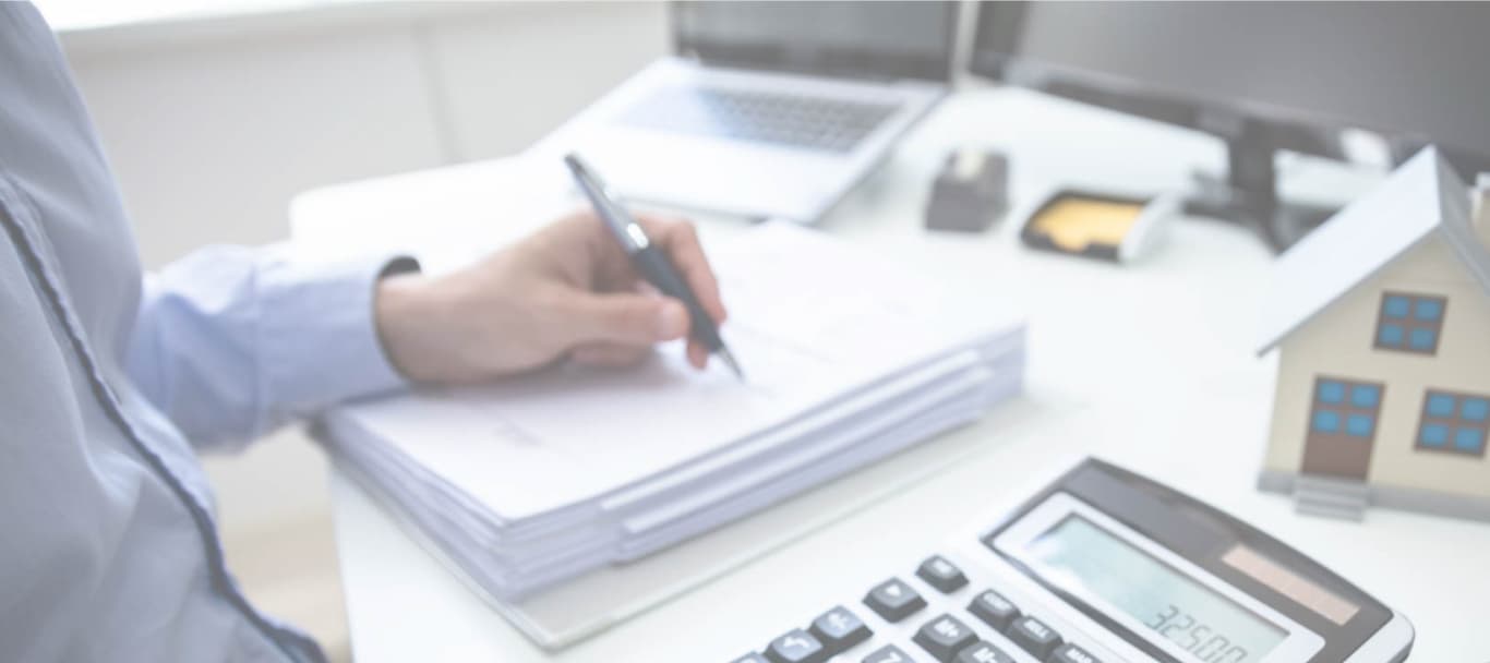 Tasación de una propiedad sobre un escritorio con calculadora y planos