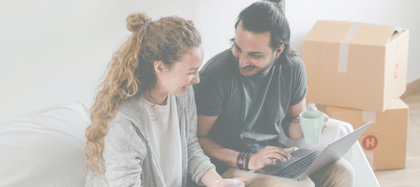 Pareja mirando propiedades en una notebook en su living